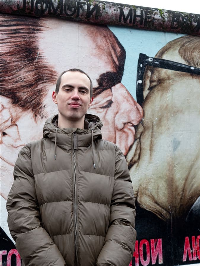 Artemiy Vrubel standing in front of the Bruderkuss mural at the East Side Gallery